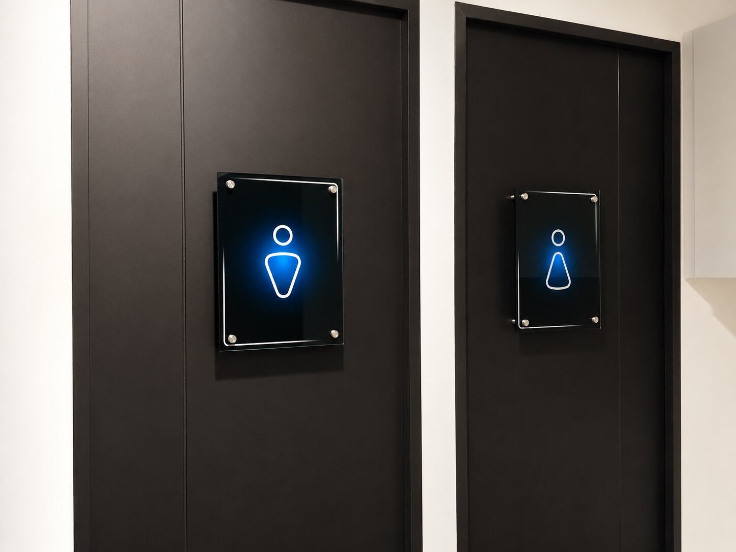 Iconos de baño en acrílico retroiluminado sobre puertas de oficina